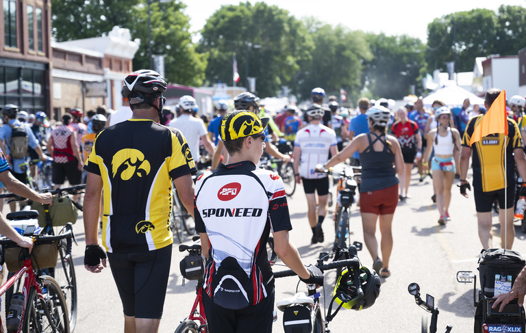 A pair of Hawkeye fans walks their bikes through a pass-through town during Day 1 of the 462-mile ride across the northern part of Iowa.