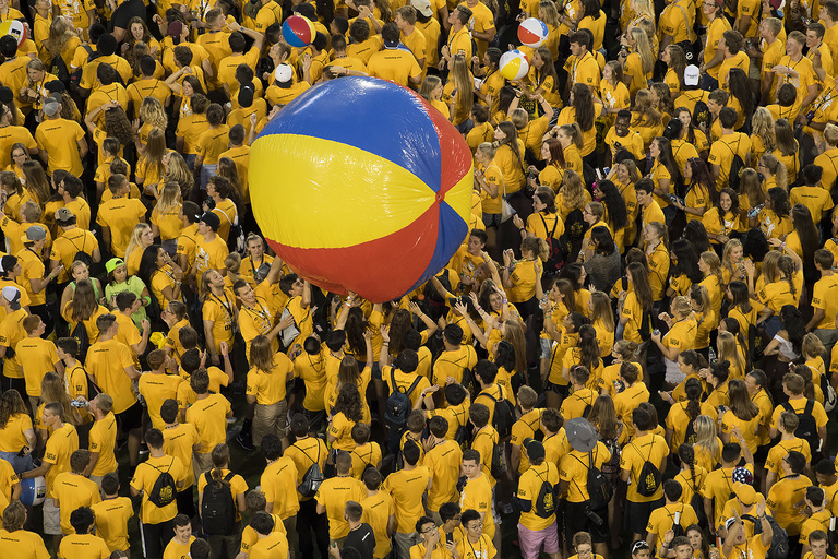 Students in gold shirts bouncing a beach ball