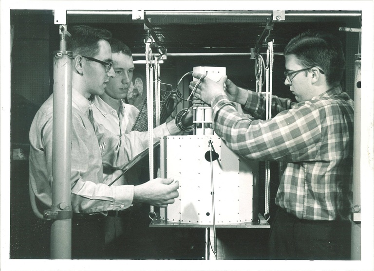 In 1961, Ray Trachta, left; Don Gurnett, left center; and Bill Whelpley, right, assemble prototype parts of the Injun 1 spacecraft at the University of Iowa.