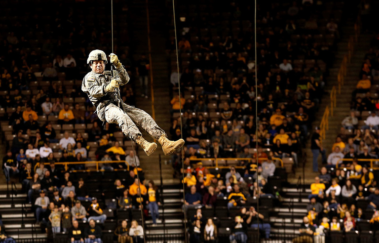 Lieutenant Colonel Buettner rappels from the rafters of Carver as part of a demonstration to celebrate the 100th Year Anniversary of the Reserve Officers’ Training Corps during a UI wrestling meet. 