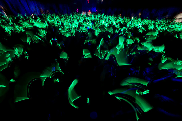 Crowd of people in dark room waving glow sticks