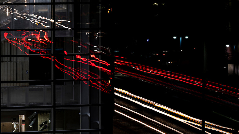 Traffic lights at night reflected in music building's glass exterior