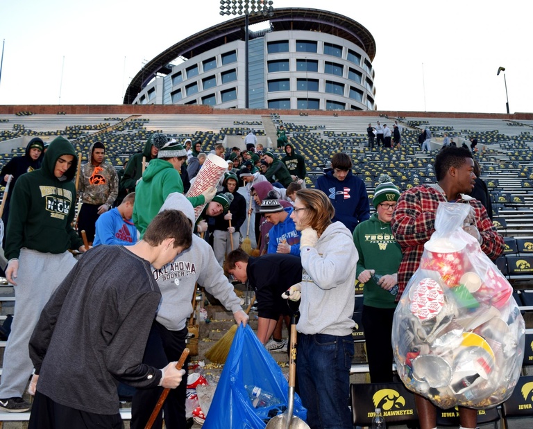 students cleaning up football stadium seats