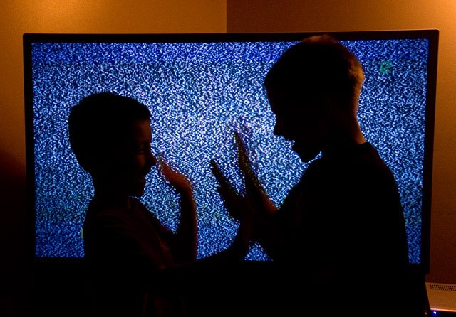 children playing in front of static-filled tv