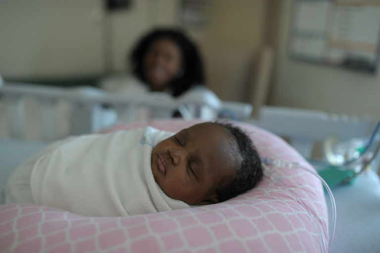 infant swaddled in hospital bed
