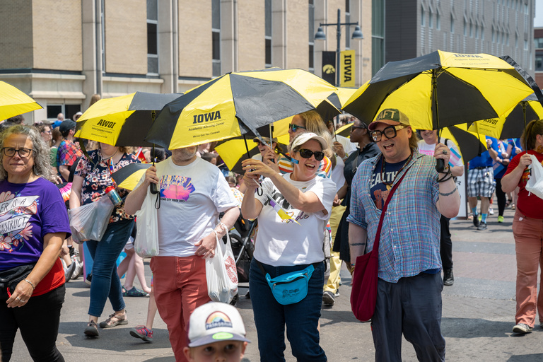 The UI Academic Advising Center walks the parade with black and gold umbrellas to stay cool during a very warm Saturday in Iowa City.