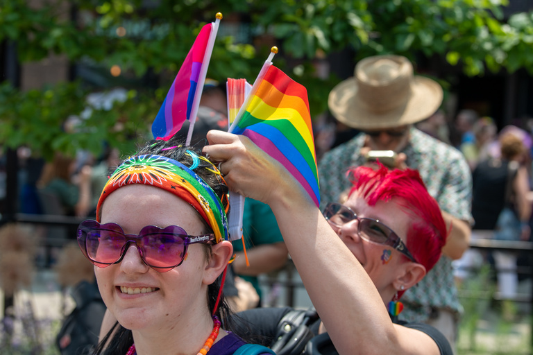 A parade attendee gets help attaching flags to their head during the Pride festival on June 17, 2023.