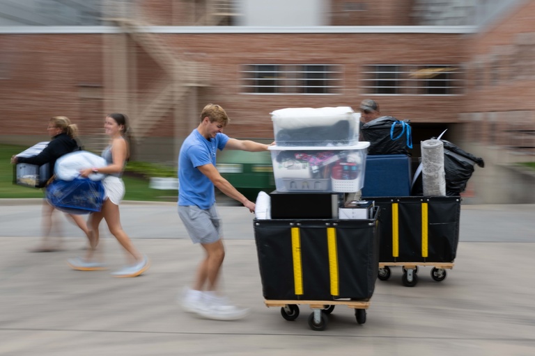 Student pushing a cart stacked full of items