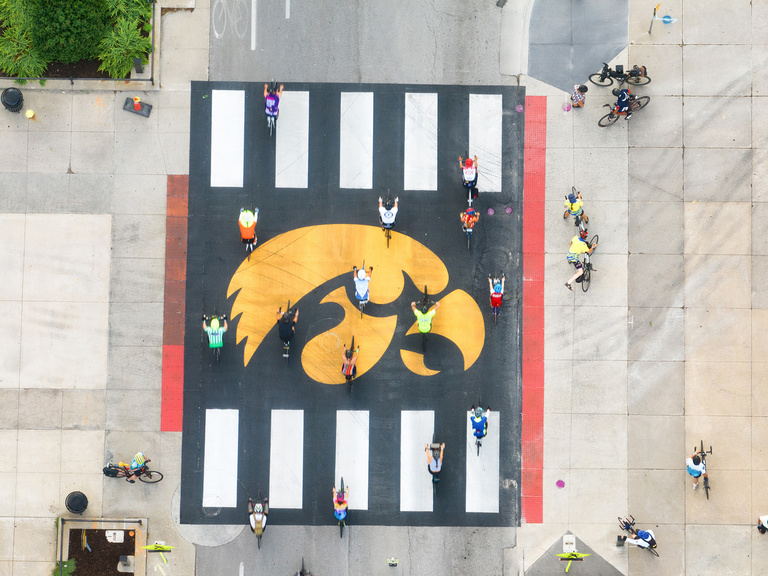 cyclists riding across a crosswalk adorned with a large tigerhawk