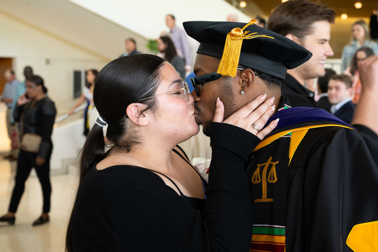 Graduate receives a kiss a commencement