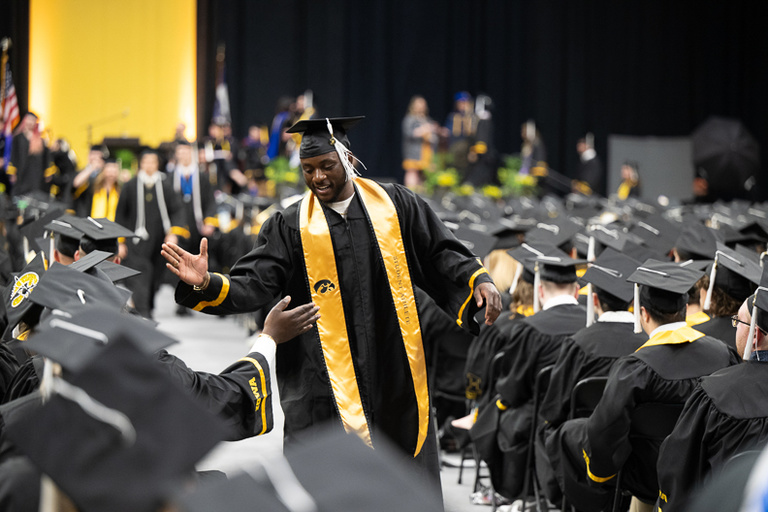 Graduate giving out high-fives at commencement