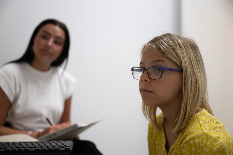 Suzette Ruiter, an 11-year-old from Hudson, Iowa, prepares for an eye-tracking/word-recognition task as part of the Growing Words Project, which seeks to understand how children recognize and learn words. In the background is Eva Kelly, a research assistant in the Mechanics of Audiovisual Categorization lab that includes the Growing Words study.