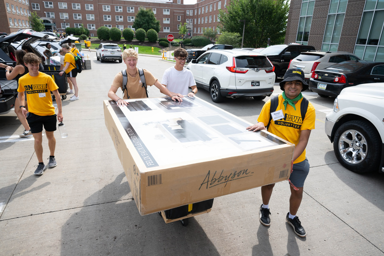 People moving a box into the residence halls