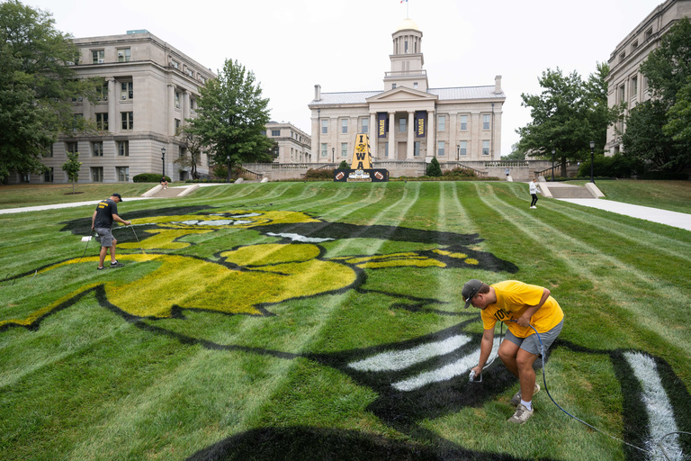 People spray painting Tigherhawk on Pentacrest