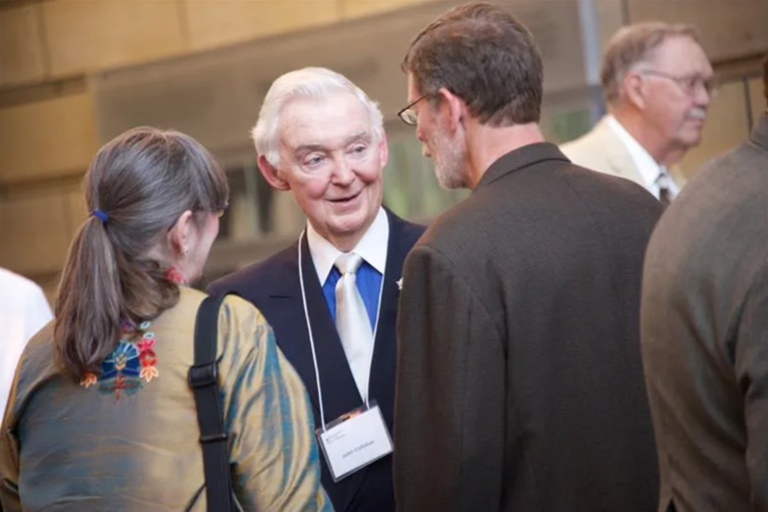 Photo of John Colloton speaking to colleagues