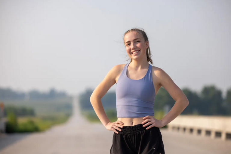 Grace Lidgett, runner and cystic fibrosis patient, standing on a rural road.