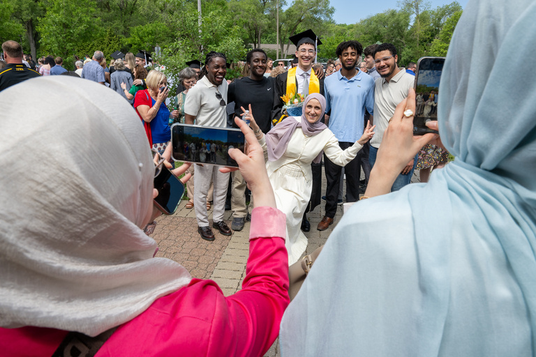 A family poses with their graduate for photos on the Pentacrest