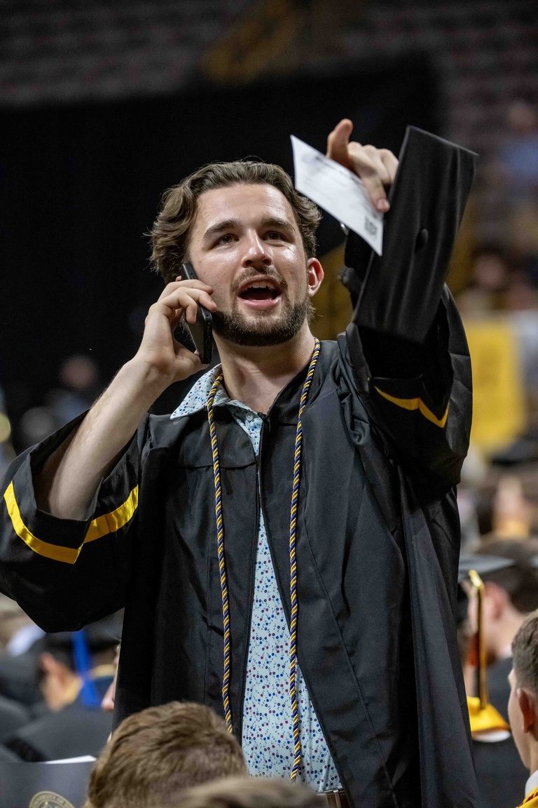 A student calls his family on his cell phone and points at them