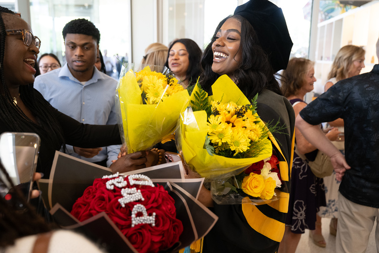 A graduate receives three bundles of flowers