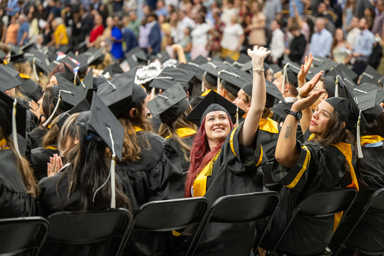 A graduate waves to the crowd