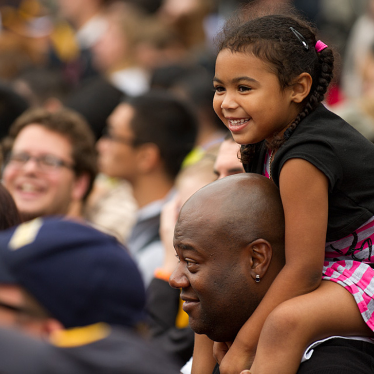 Girl sits on man's shoulders