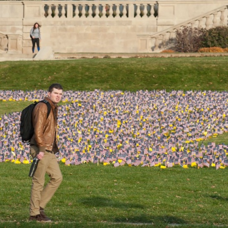 Students walk past the Pentacrest flag display