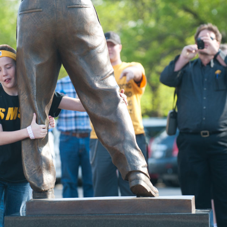 young fan wrestles with statue