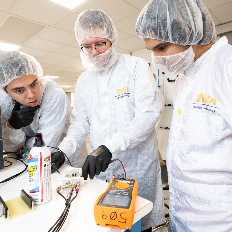 UI students Nikolas Vinovich, Sasha Wemmie, and Halit Bagdu discuss voltage readings from one of the electronics circuit boards. They and other students assembled and tested hundreds of circuit boards that will be used for DUNE, an international effort to study neutrinos, a highly elusive particle that could explain how the universe formed and how it’s evolved.