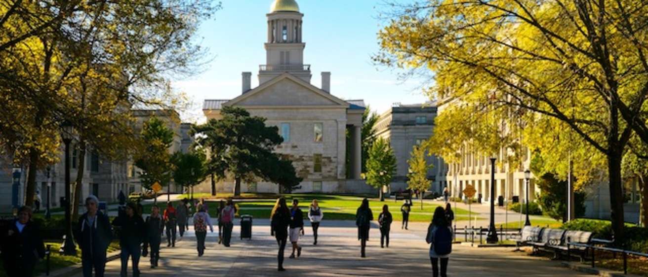 Students walk across the T. Anne Cleary walkway with the Old Capitol in the background.