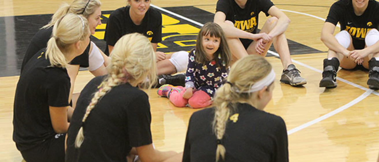 Lucy Jane Roth sits in the middle of a circle of UI volleyball players