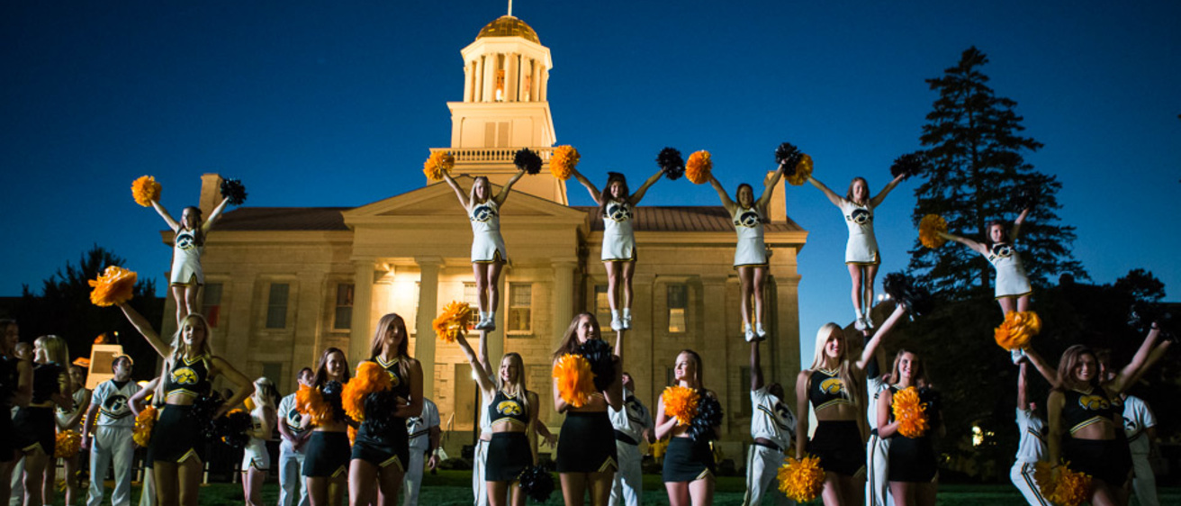 A group of male and female cheerleaders performing in front of a building