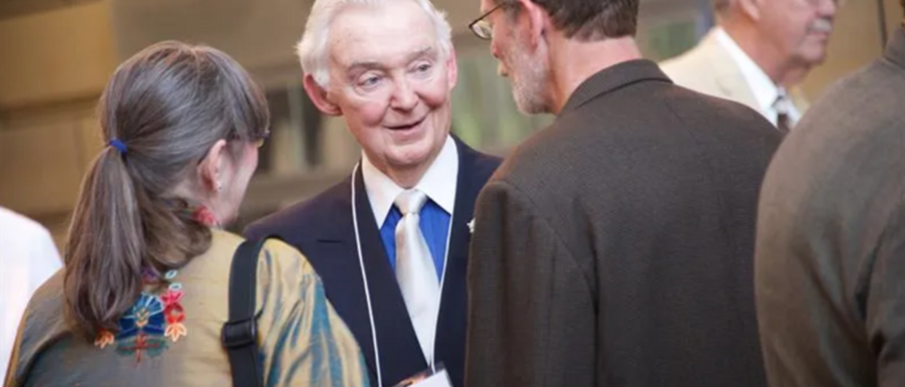 Photo of John Colloton speaking to colleagues