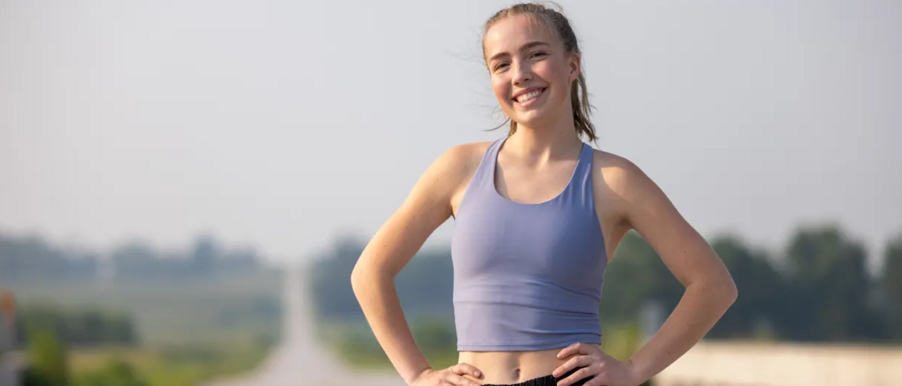 Grace Lidgett, runner and cystic fibrosis patient, standing on a rural road.