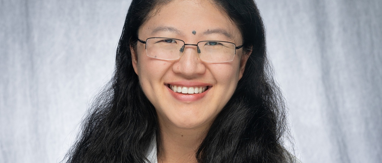 Susan Shen, with long black hair wearing glasses and white coat.
