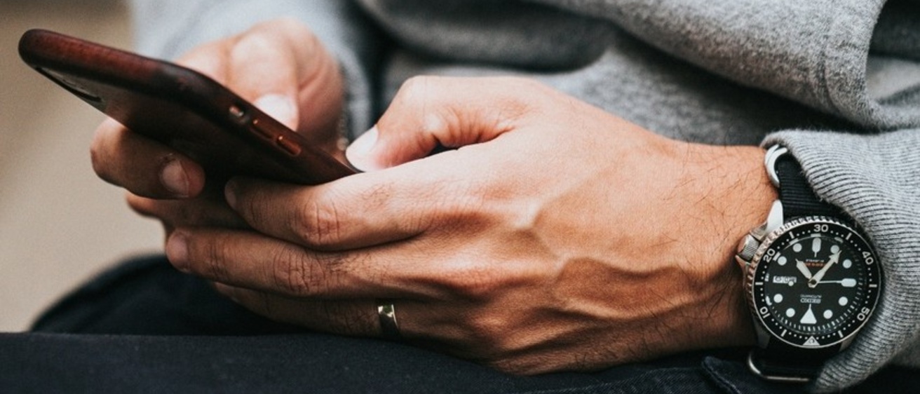 Hands holding a cell phone and scrolling through content.