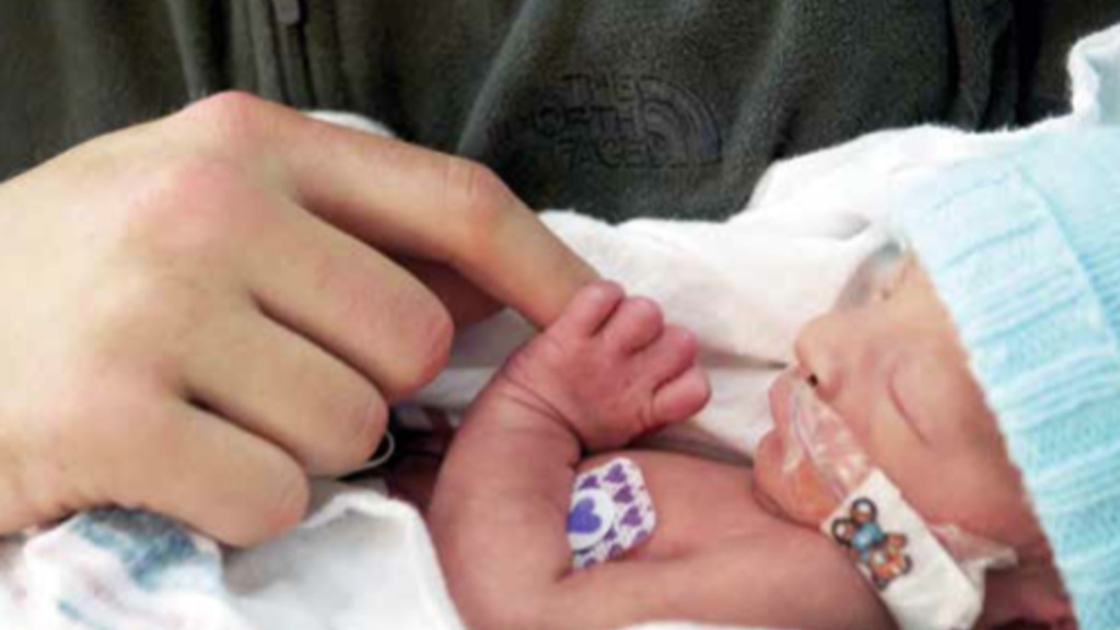 a photo of a premature baby holding someone&#039;s finger at UI Health Care