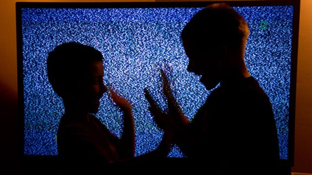 Photo of a silhouette of two children playing in front of big screen TV, photo by Tim Schoon of University Communication and Marketing