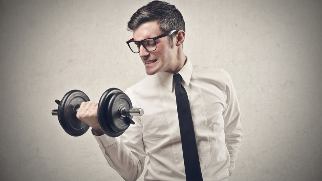A guy wearing a tie flexes his muscles using a dumbell 