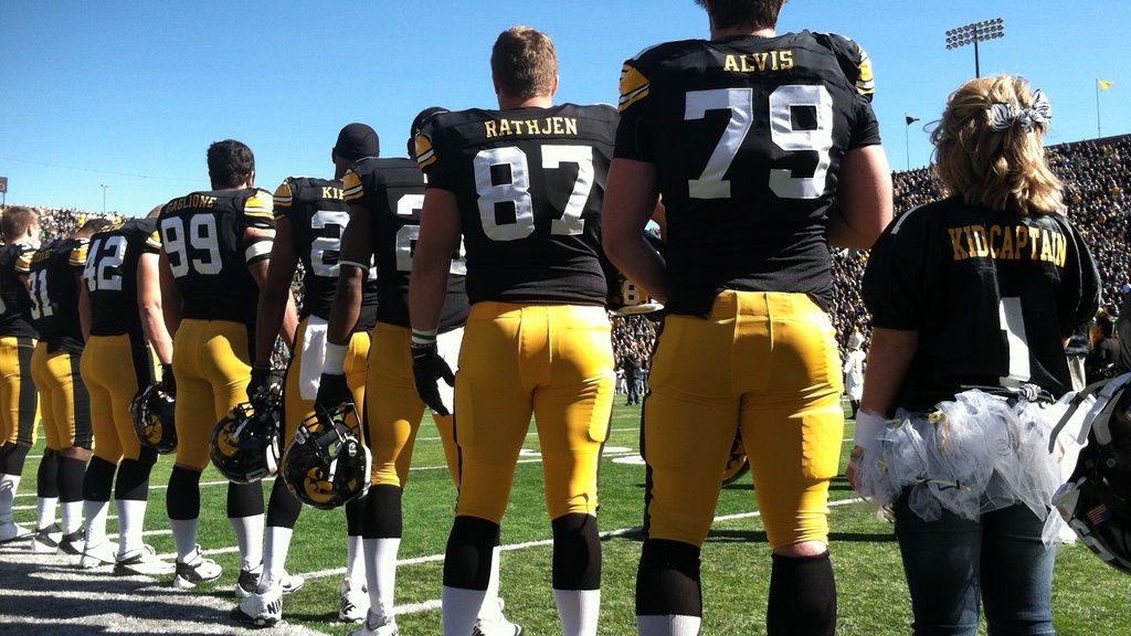 2012 Kid Captain Brandi Yates stands with the Iowa Hawkeyes during a home football game in 2012.