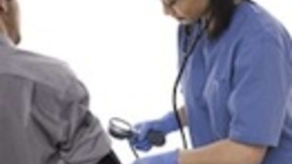 Nurse in scrubs takes a man&#039;s blood pressure