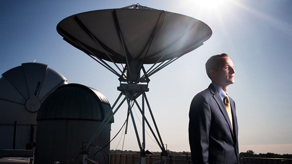 University of Iowa faculty member Daniel Newton stands on top of Van Allen Hall on Iowa's campus