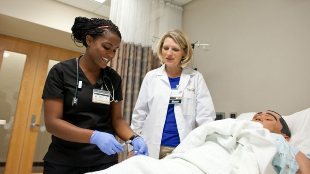 Nursing student and instructor around hospital bed