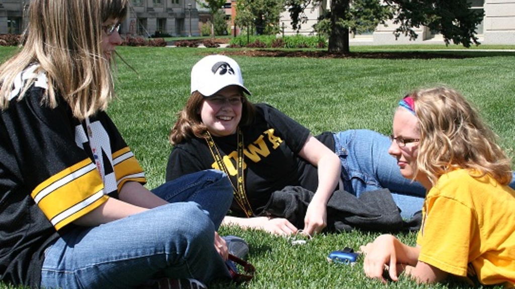 Image of 3 UI students lounging on the UI Pentacrest lawn