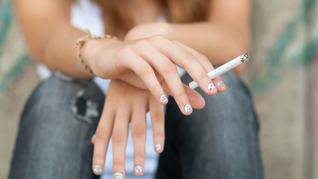 hands holding a lit cigarette