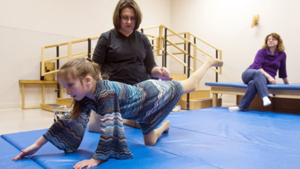 young girl receiving assistance to stretch muscles