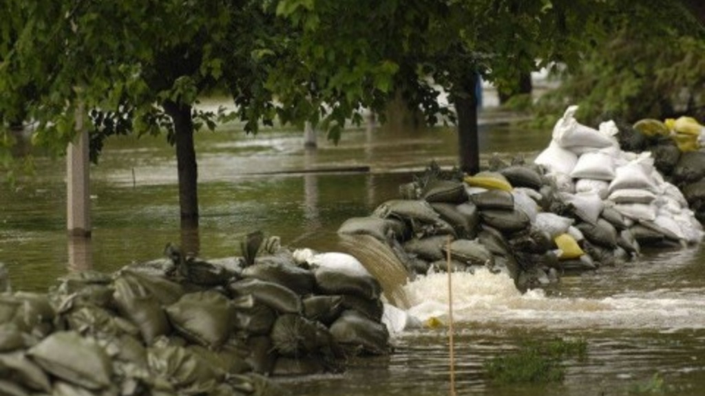 A photo of water moving over sandbags and around trees during the Iowa flooding of 2008 in Iowa City