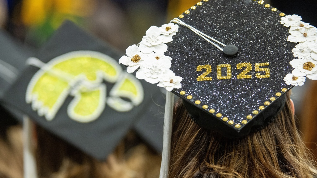 A close-up of a graduation cap adorned with glitter, sequins and flowers.