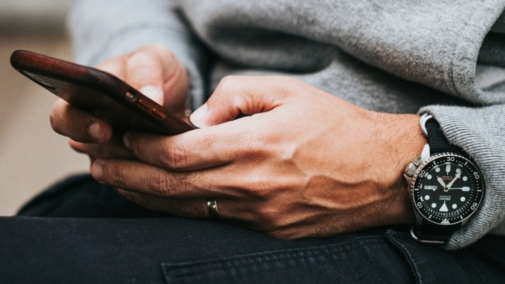Hands holding a cell phone and scrolling through content.