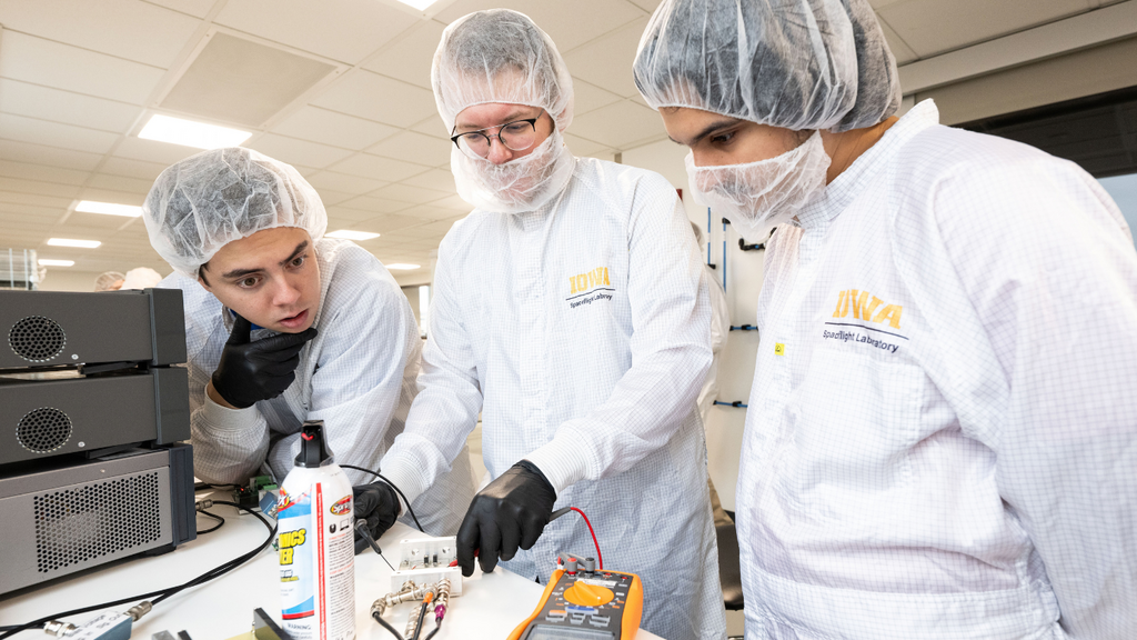 UI students Nikolas Vinovich, Sasha Wemmie, and Halit Bagdu discuss voltage readings from one of the electronics circuit boards. They and other students assembled and tested hundreds of circuit boards that will be used for DUNE, an international effort to study neutrinos, a highly elusive particle that could explain how the universe formed and how it’s evolved.
